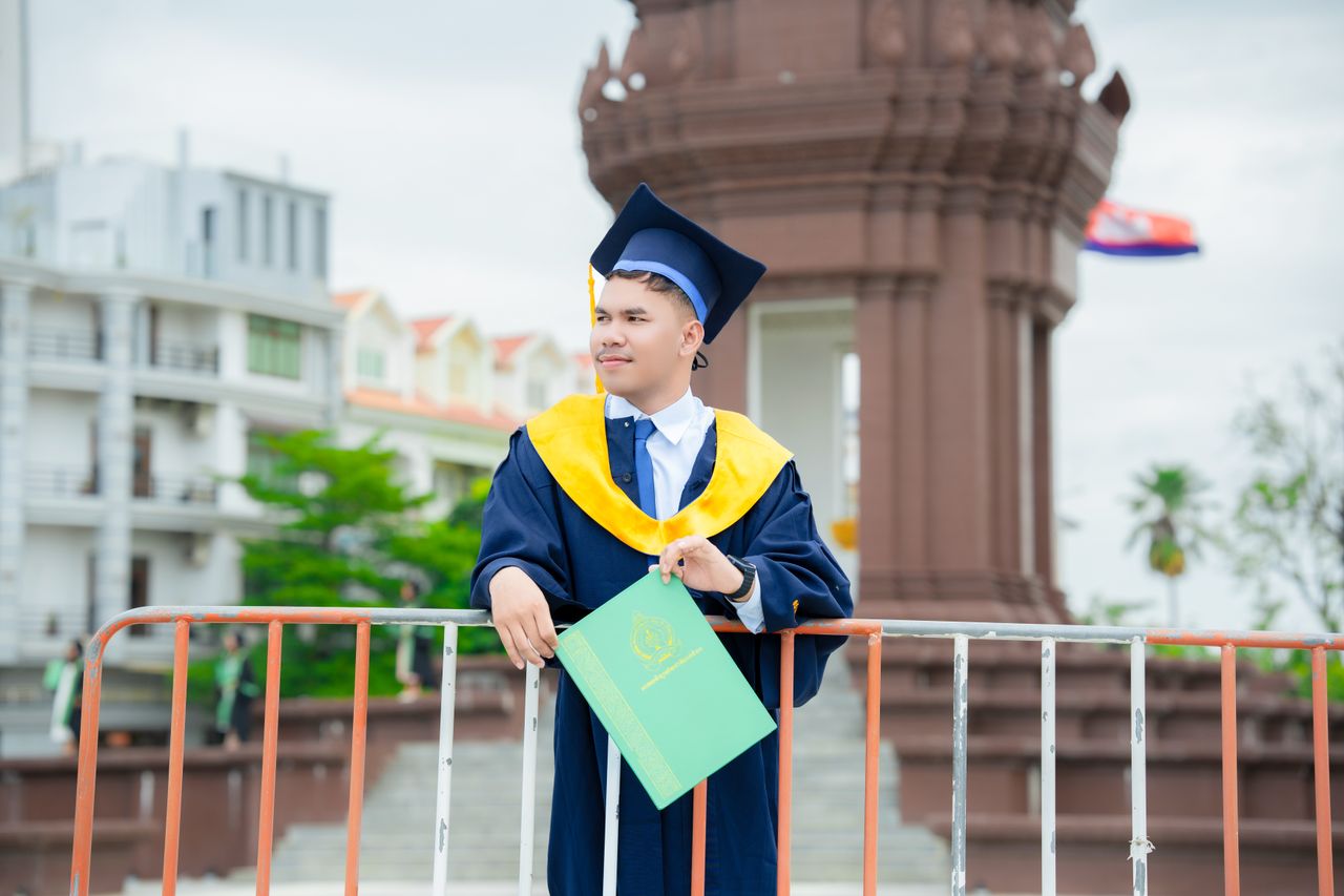 Home Young man celebrates graduation in Battambang, Cambodia with cap and gown.
